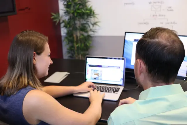 One colleague showing a client something on their laptop