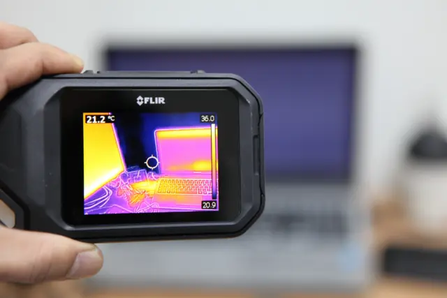 Thermal imaging camera identifying heat loss from a laptop and workspace