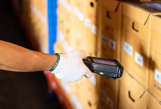 Warehouse worker scanning packaged goods for product carbon footprint data