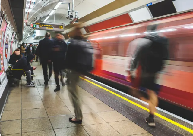 Commuters on a London Underground platform as a train arrives